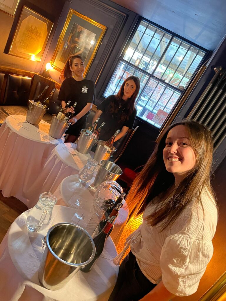 Three women gathered around a table, each holding a wine glass, engaged in conversation and enjoying their time together.