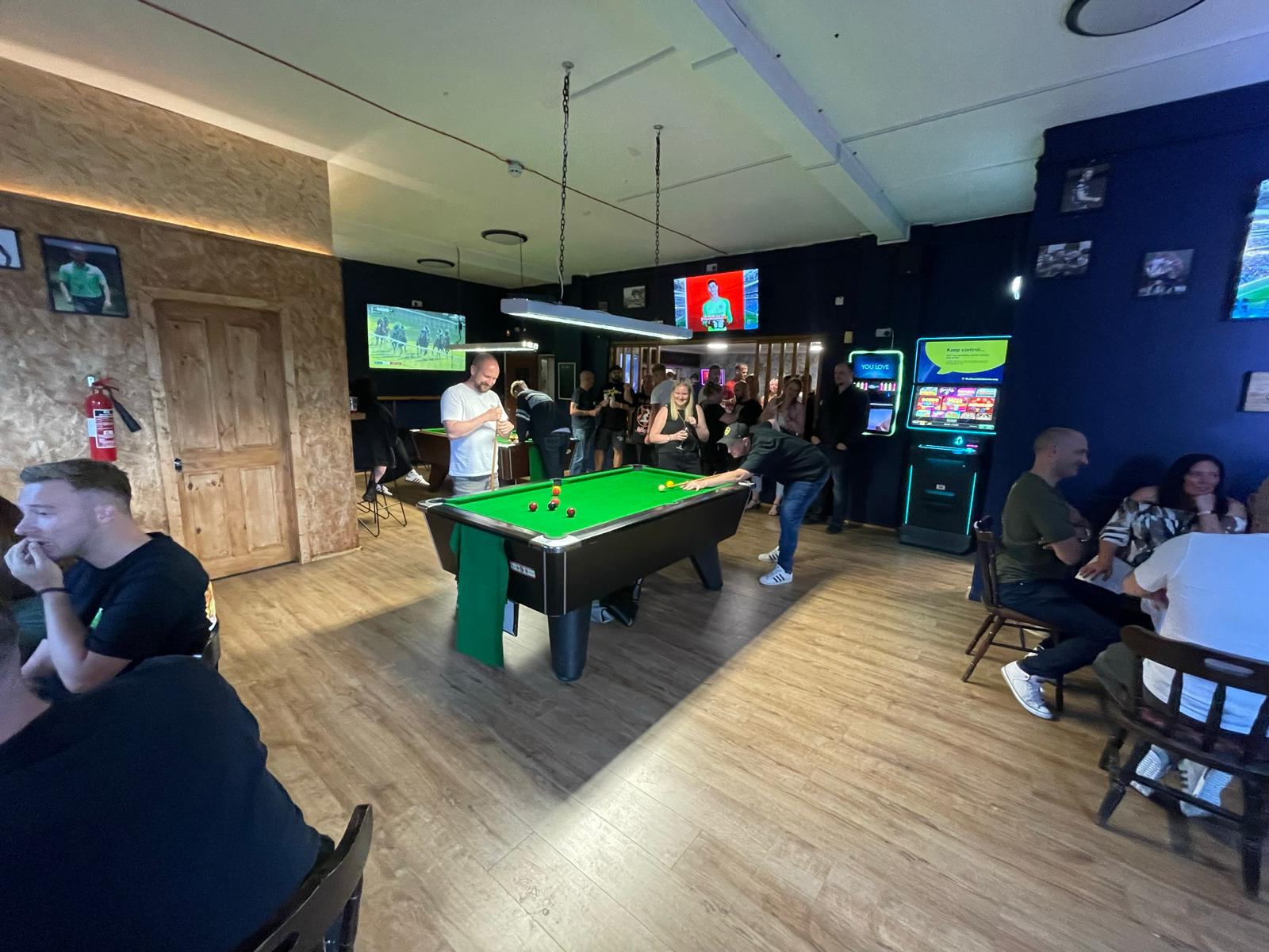 A lively bar scene featuring a group of individuals engaged in a game of pool, showcasing camaraderie and enjoyment.