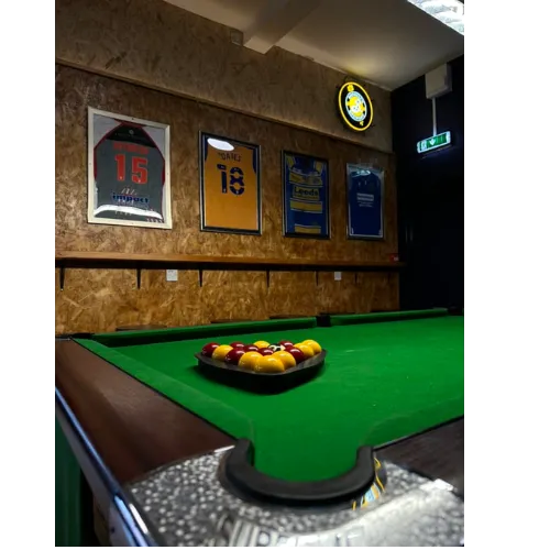 A pool table in a room adorned with framed pictures on the walls, creating a vibrant and inviting atmosphere.